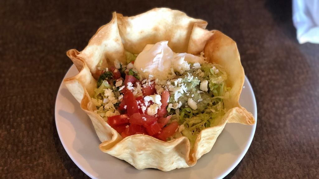 Fajita Taco Salad · Fajita-style chicken or beef in a crispy flour tortilla shell with beans, lettuce, tomatoes, cotija cheese, and guacamole.