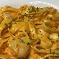 Seafood Trio · Scallops, shrimp, and salmon tossed in a roasted red pepper cream sauce with fettuccine pasta.