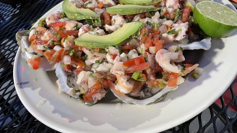 Ostiones Preparados · Fresh oysters served in its own shell with ceviche, lemon, pico de gallo and avocado.