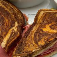 Rueben · Thinly sliced corned beef with sauerkraut and melted Swiss cheese on grilled marble rye with...