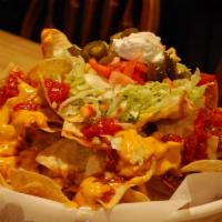 Titanic Nachos · Crisp tortillas piled high with spicy cheese sauce, chili con carne, lettuce, tomato, sour c...