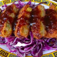Japanese Korokke · Vegan. 3 fried potato & vegetable croquettes on a bed of shredded cabbage with bulldog sauce.