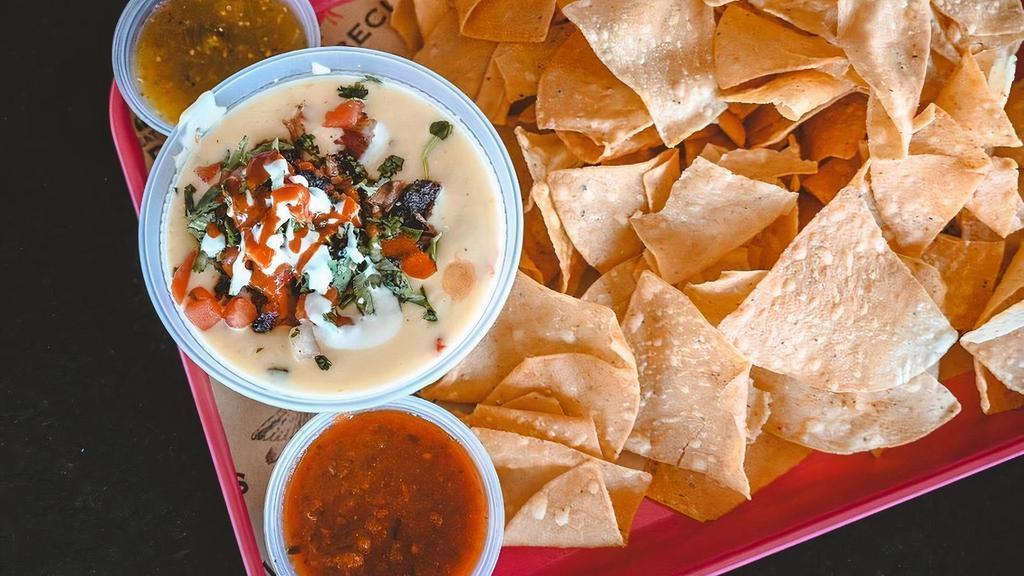 Best Queso-Nario · Tortilla Chips, Queso, Chopped Brisket, Pico, Lime Crema, Valentina, Cilantro. Served with Salsa Roja & Salsa Verde on the side.