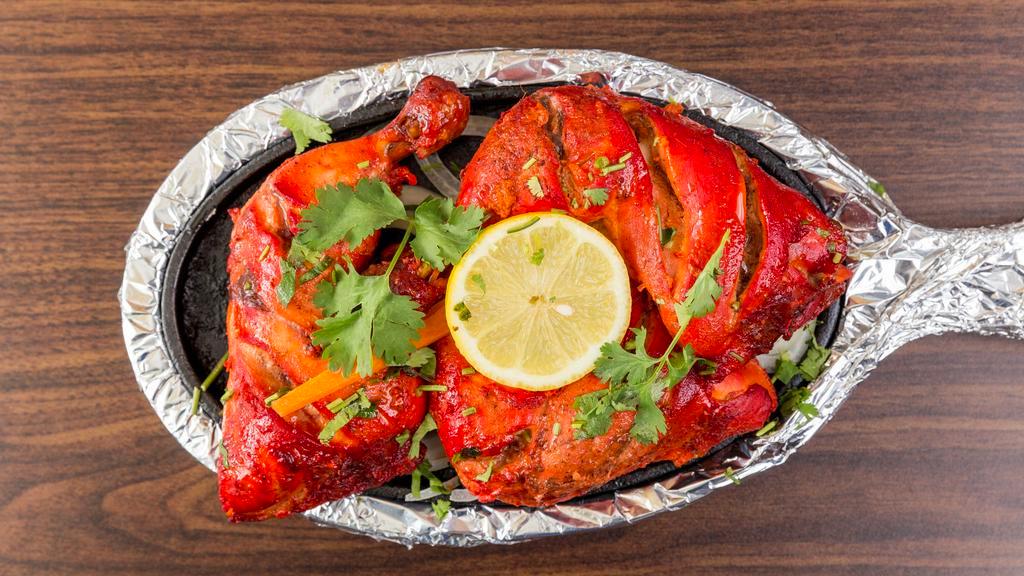 Tandoori Chicken · Tender spring chicken marinated in yogurt with a blend of imported mild spices and herbs. Served with grilled onions, green peppers, and lemon.