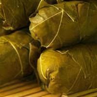 Stuffed Grape Leaves · Vine grape leaves stuffed with rice and a blend of Mediterranean herbs and spices atop a bed...