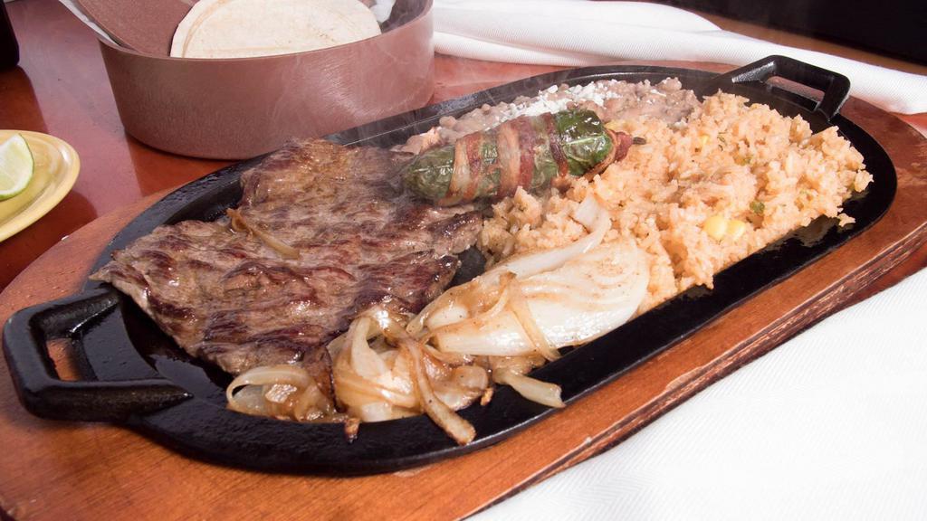Carne Asada Skillet · Thin skirt steak cooked with grilled onions with a jalapeño popper on top. Served with refried or black beans and rice in a hot skillet. Guacamole, romaine mix and tortillas served on the side.