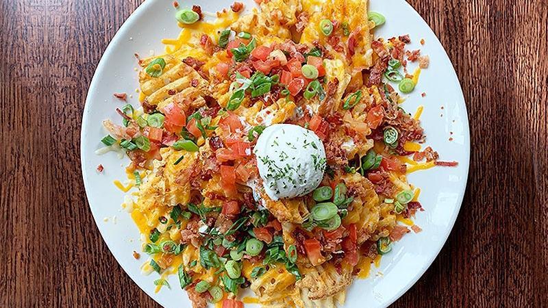 Idaho Nachos Appetizer · crispy waffle fries piled high with melted cheddar jack cheese, bacon, roma tomato, green onion and sour cream.