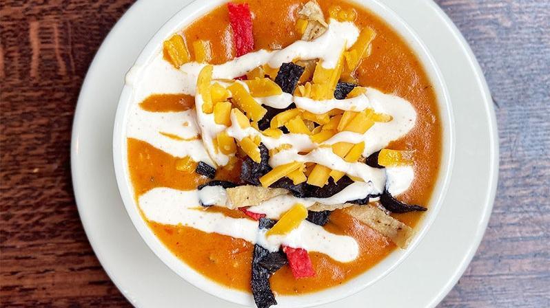 Cheesy Chicken Tortilla Soup · made with roasted chicken, red chilis, cream and cheddar cheese. topped with crunchy tortilla strips, shredded cheddar and sour cream.
