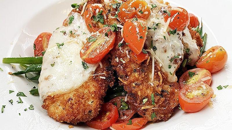 Chicken Tuscano · Lightly breaded, pan fried chicken breast topped with melted provolone cheese, and served over garlic mashed potatoes, sauteed green beans, and grape tomatoes in a white wine butter sauce.
