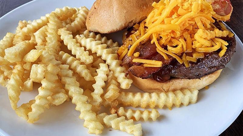 Bedda Chedda Burger · half-pound gc signature beef blend, house-made BBQ sauce and crisp bacon, piled high with shredded cheddar cheese on a brioche bun.