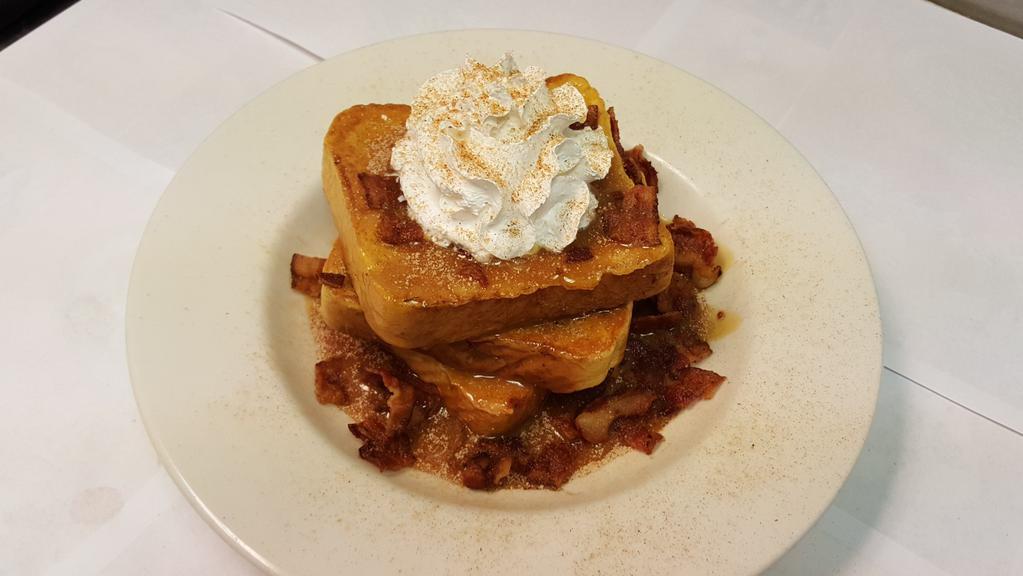 Cinnamon Caramel French Toast · Three slices of french toast served in a bowl with crumbled bacon topped with hot caramel and whipped cream dusted with cinnamon.