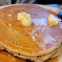 Buttermilk Pancakes · Three large fluffy pancakes with butter and warm syrup.