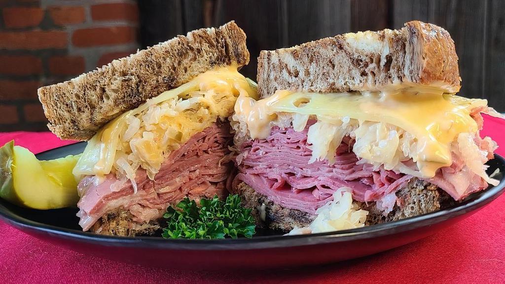 Traditional Corned Beef Reuben · Thinly sliced lean corned beef topped with Schmidt’s sauerkraut, special dressing, und melted Swiss cheese grilled on pumpernickel, served with our German Potato Salad.