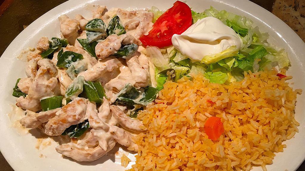 Pollo A La Crema · Grilled chicken breast strips topped with poblano peppers and sour cream special sauce. Served with rice, lettuce, tomatoes, sour cream, and tortillas.