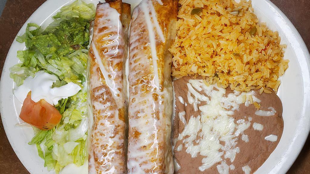 Chimichanga Dinner · Two chimichangas (one beef, one chicken) topped with our special cheese sauce. Served with guacamole-sour cream salad and refried beans.