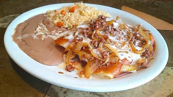 Enchiladas Toluca · Three enchiladas: beef tips, chicken and cheese smothered with chorizo and grilled onions. Topped with red enchilada sauce and our special cheese sauce. Topped with enchilada sauce and served with rice and refried beans.