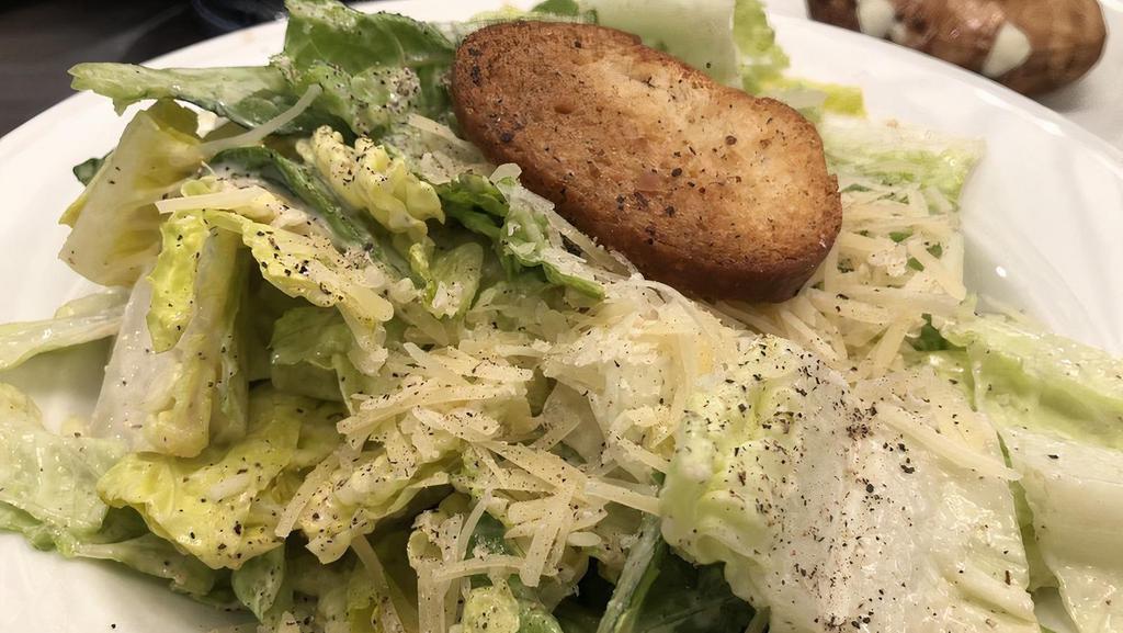 Caesar Salad · Romaine lettuce tossed in our Caesar dressing, croutons and topped with shredded Parmesan cheese.