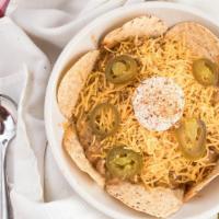 Nola Nachos · Tortilla chips covered in drunken chicken and white chili with cheddar cheese, sour cream an...