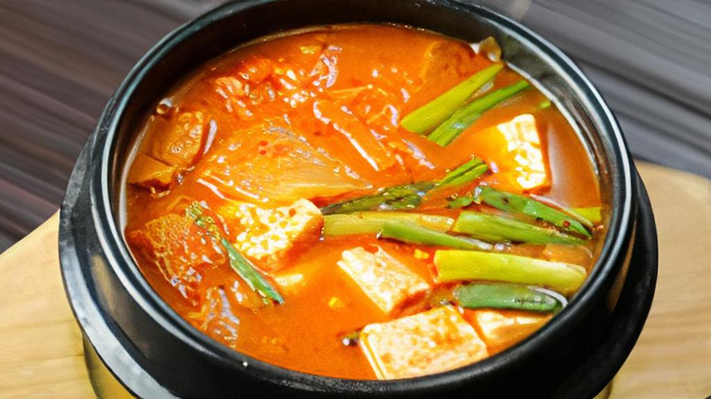 Kimchi Chigae · Kimchi, pork, tofu, fish cake, scallions, mushrooms and spicy pepper flakes in boiling kimchi broth.