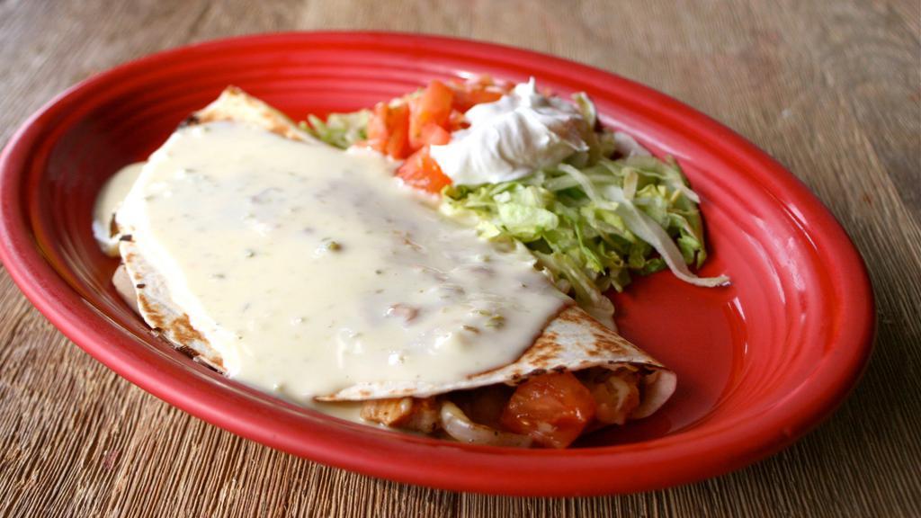 Quesadilla De Fajitas · One quesadilla with your choice of marinated steak or chicken, green peppers, onions and tomatoes. Topped with chile con queso. Served with refried beans. Spanish rice, shredded lettuce, tomatoes and sour cream.