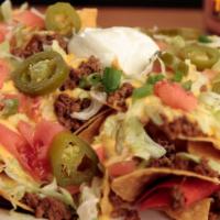 Texas Size Beef Nachos · Homemade fried tortilla chips topped with seasoned ground beef, creamy nacho cheese, diced t...