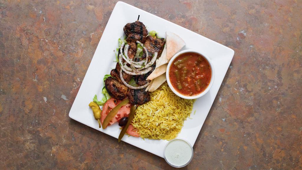 Lamb Kebab Dinner · Grilled seasoned lamb with garlic and black pepper served with rice, green beans, tahini sauce, and pita.