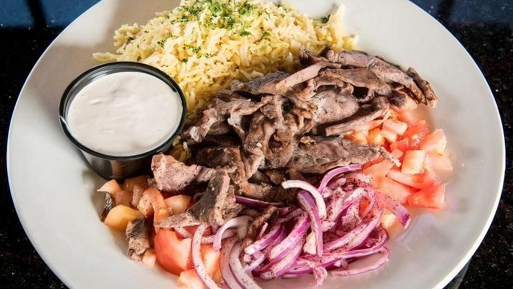 Beef Shawarma · Marinated beef seasoned and slowly cooked on a rotisserie. Thinly sliced and topped with tomatoes, onions, and sumac. Served with basmati rice and tahini sauce.
