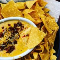Chorizo Queso Dip · Warm Cheddar dip with jalapeño and chorizo served with crispy corn chips.