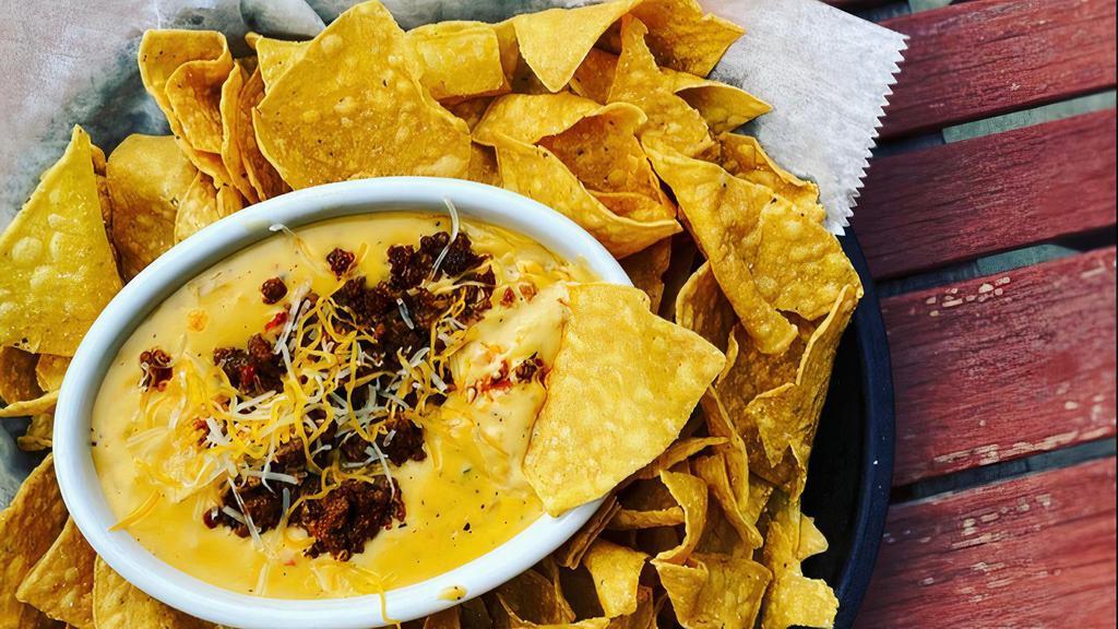 Chorizo Queso Dip · Warm Cheddar dip with jalapeño and chorizo served with crispy corn chips.