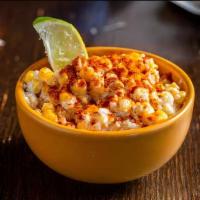 Easy As Esquites · Mexican sweet corn in a cup topped with mayo, Mexican cheese, chili powder, and a lime wedge.