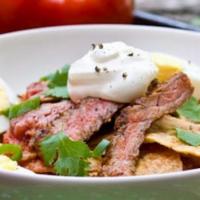 Chilaquiles With Steak · tortilla chips sauteed in a tangy salsa with beef.topped with Mexican cheese and served with...