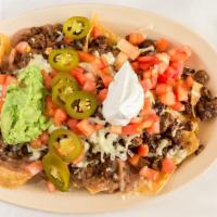 Nacho Supremos · A mound of tortilla chips topped with ground beef and chihuahua cheese beans, tomato, jalape...