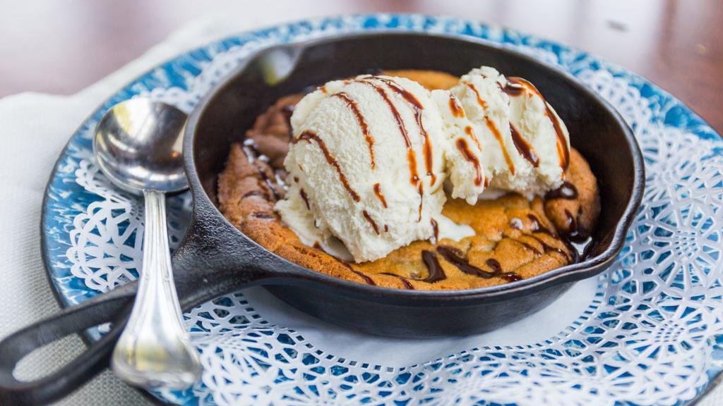 Skillet Chocolate Chip Cookie · Baked chocolate chip cookie topped with ice cream and chocolate sauce.