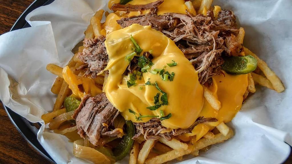 Philly Cheese Steak Fries · Big boat of fresh golden crispy fries topped with cheddar cheese sauce, slow roast beef, sautéed onions and peppers.