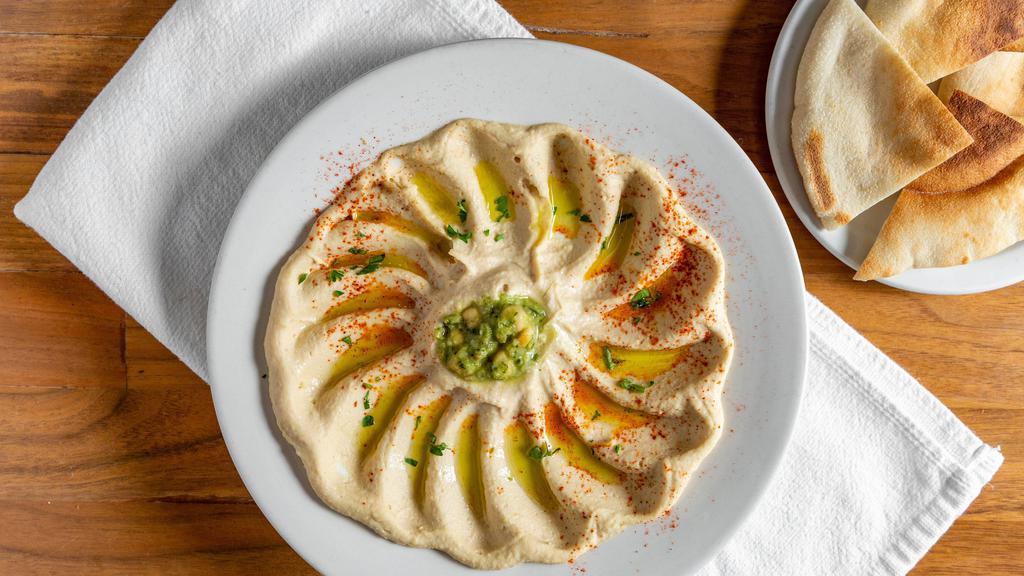 Hummus · Gluten Free. Vegan. Simmered chickpeas pureed with tahini, lemon juice and garlic. Garnished with sumac, olive oil, parsley, and hot sauce. Served with pita bread.