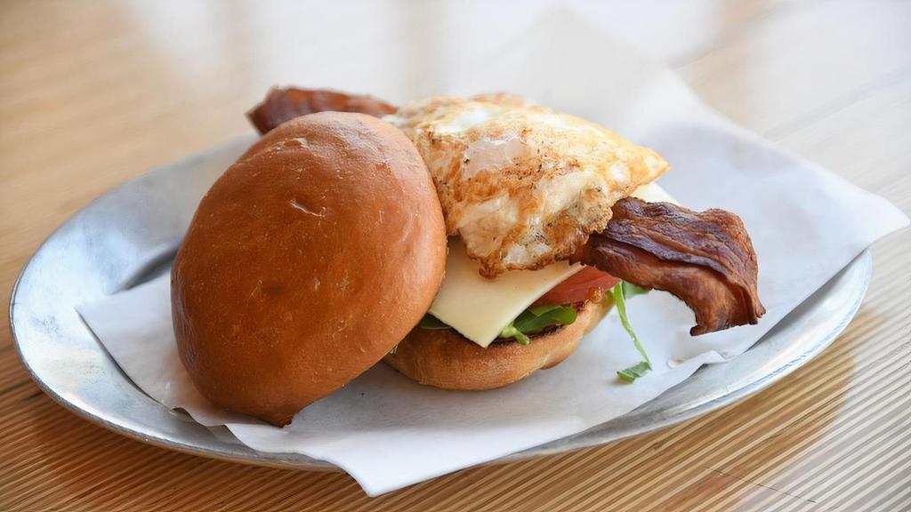 Fried Egg Blt · Fried local/free range egg, applewood smoked bacon, baby arugula, sliced tomatoes, and sharp white cheddar cheese on a toasted egg bun with Unspread