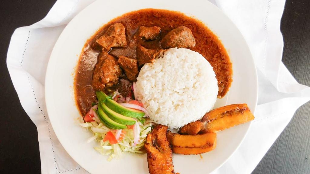 Seco De Chivo · Goat stew served with rice, sweet plantain, salad and avocado.