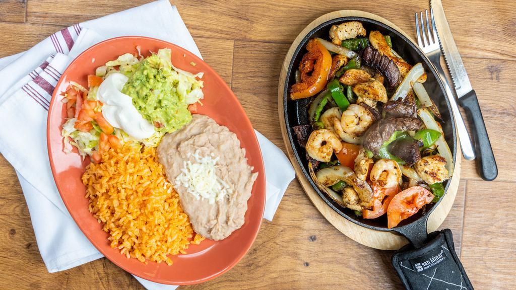 Texana Fajitas · Chicken , steak, and shrimp-
delicately spiced and marinated with onions and bell peppers. Served with Spanish rice, refried beans, sour cream, guacamole lettuce, tomato, and your choice of corn or flour tortillas.