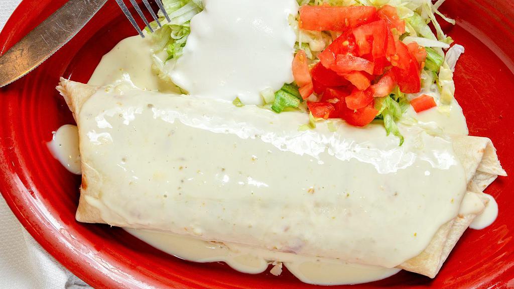 #76. El Grande Burro · A big burrito stuffed with your choice of steak or chicken rice and beans inside with melted cheese on top. Served with lettuce, sour cream and pico de gallo.