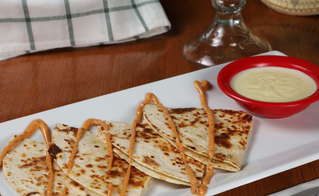 Quesa-Time · A large cut-up cheese quesadilla drizzled with chipotle sauce. Served with a small side of cheese dip.
