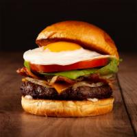 The Breakfast Burger · Beef patty, bacon, caramelized onions, melted cheddar cheese, mayo, and a fried egg on a bri...