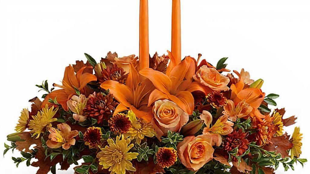 Family Gathering Centerpiece · As your loved ones gather around the table, they'll bask in the warm glow of two orange taper candles surrounded by a fantastic array of fall flowers.
Orange roses, Asiatic lilies, dark orange alstroemeria, bronze button spray chrysanthemums, yellow and rust cushion spray chrysanthemums and fall foliage are exquisitely gathered in this center-of-attention piece.