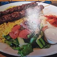 Beef Kafta Kebab (Tekkah) · Three skewers of minced beef on rice, salad, hummus, tahini sauce, and pita bread.