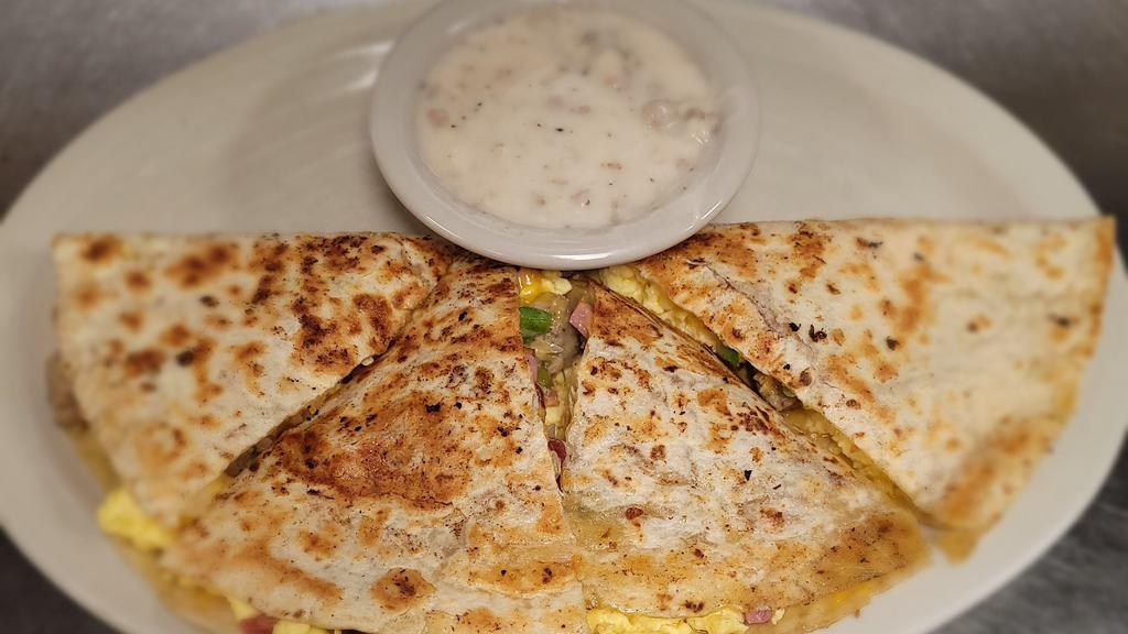 Breakfast Quesadilla · Scrambled eggs, with ham, bacon, ground sausage, green peppers, onions and shredded cheese inside a warm tortilla shell. Served with a side of sausage gravy.