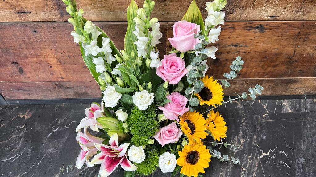 Alluring Beauty · This beautiful and elegant arrangement displayed in a wooden craft box.  (Includes: four sunflowers, four pink roses, three stargazer lilies, three white lisianthus, three white snapdragon, three trick, leather leaf, eucalyptus and three ti leaf).