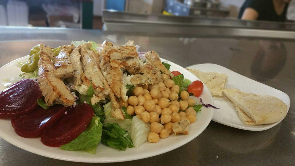 Grilled Chicken Salad · Warm tender slices of marinated chicken on a bed of greens with tomato, cheese and a hard boiled egg, with pita bread.