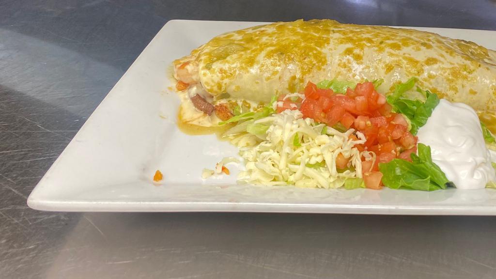 Burrito Texano · Filled with steak, chicken, shrimp, rice and black beans  inside, lettuce and sour cream. Topped with green salsa and cheese dip.