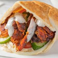Chicken Shawarma · A warm pita lined with hummus, stuffed with marinated, spit-roasted chicken with onions, cuc...