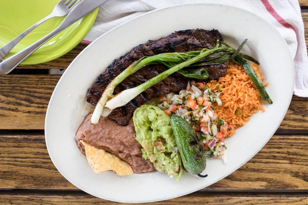 Carne Asada · Two charbroiled beef fillets served with lettuce, onions, avocado slices and tomatoes. Served with Mexican rice, beans and flour tortillas.