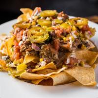 Pulled Pork Nachos · Crispy tortilla chips, layered with creamy chihuahua cheese sauce, our signature braised por...